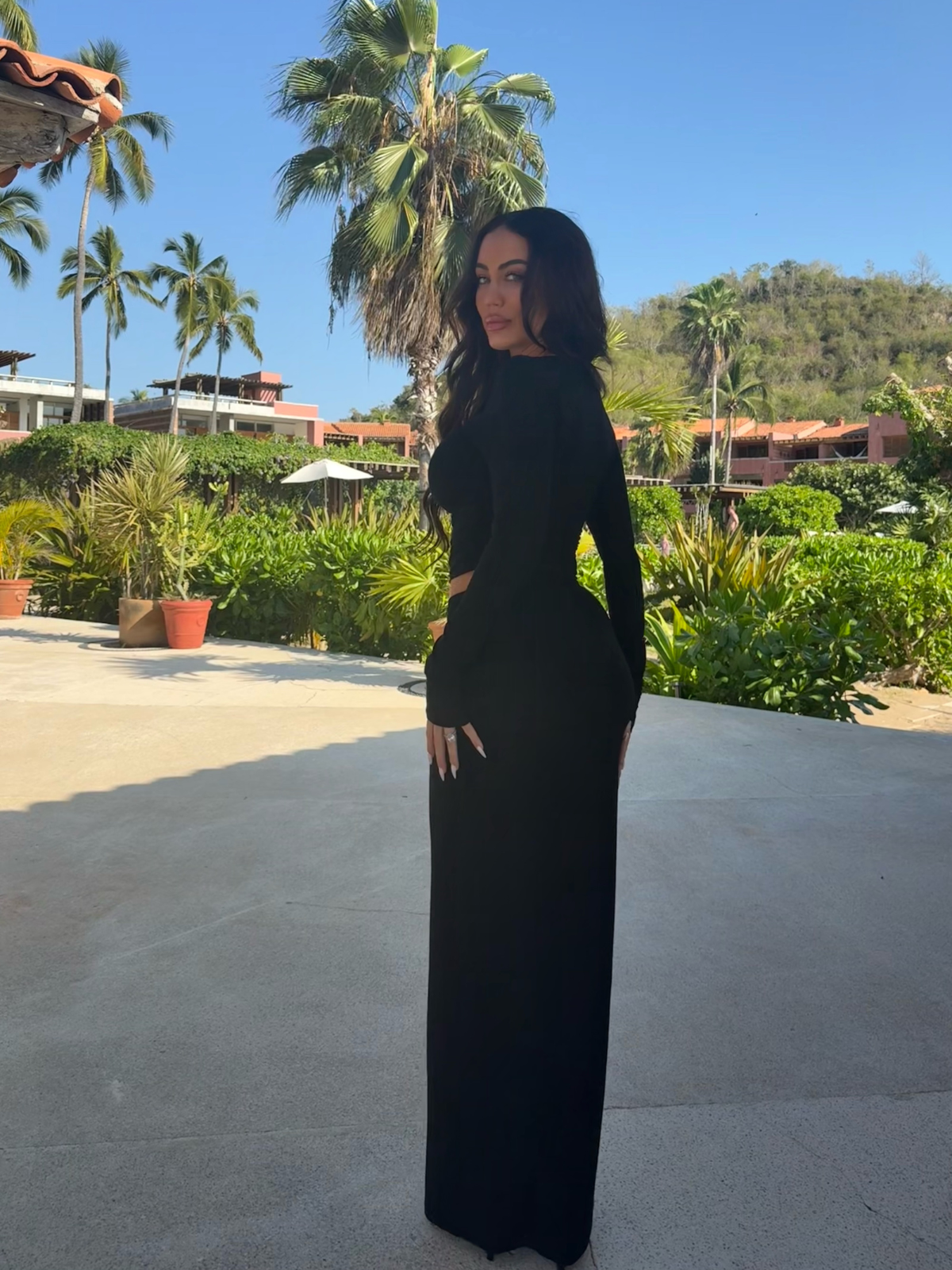 Black matching set with long sleeve crop top and bodycon maxi skirt, side view outdoors