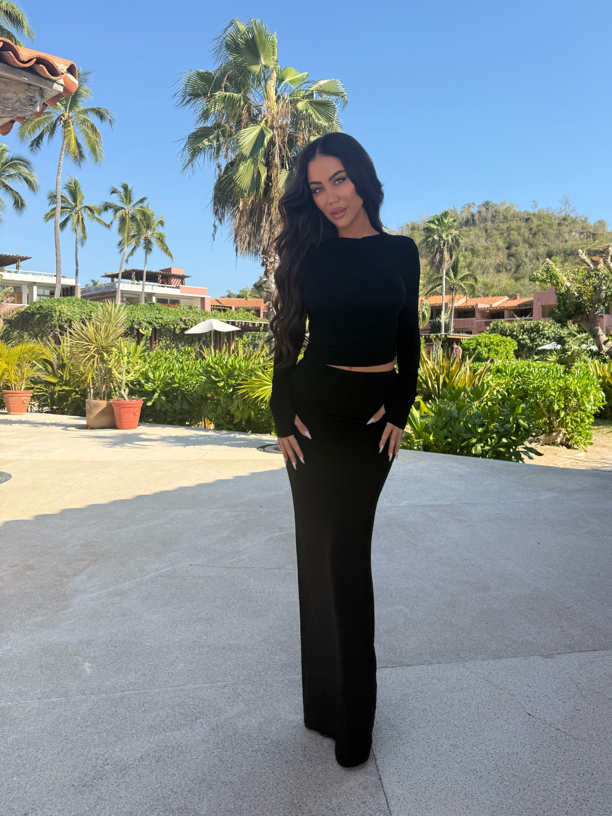 Black two piece matching set with long sleeve crop top and bodycon maxi skirt, outdoor front view