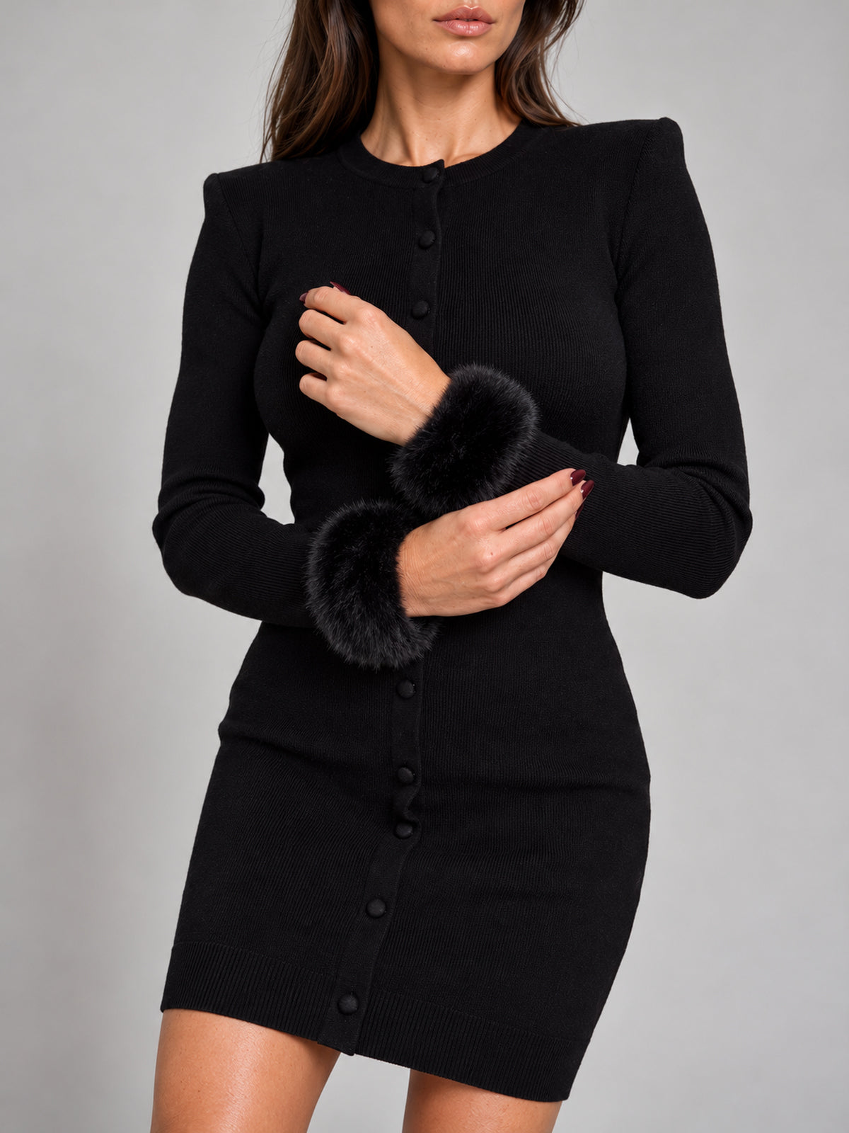 Three-quarter close-up of black faux fur slap-on cuffs with burgundy nails.