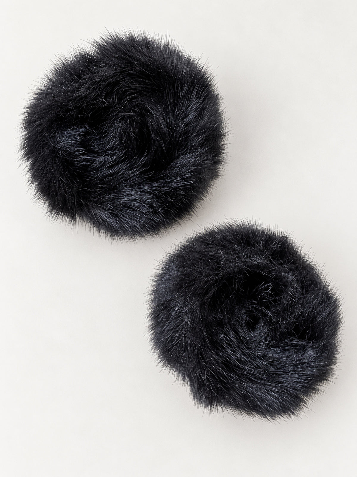 Black faux fur slap cuffs, closed pair on a light background
